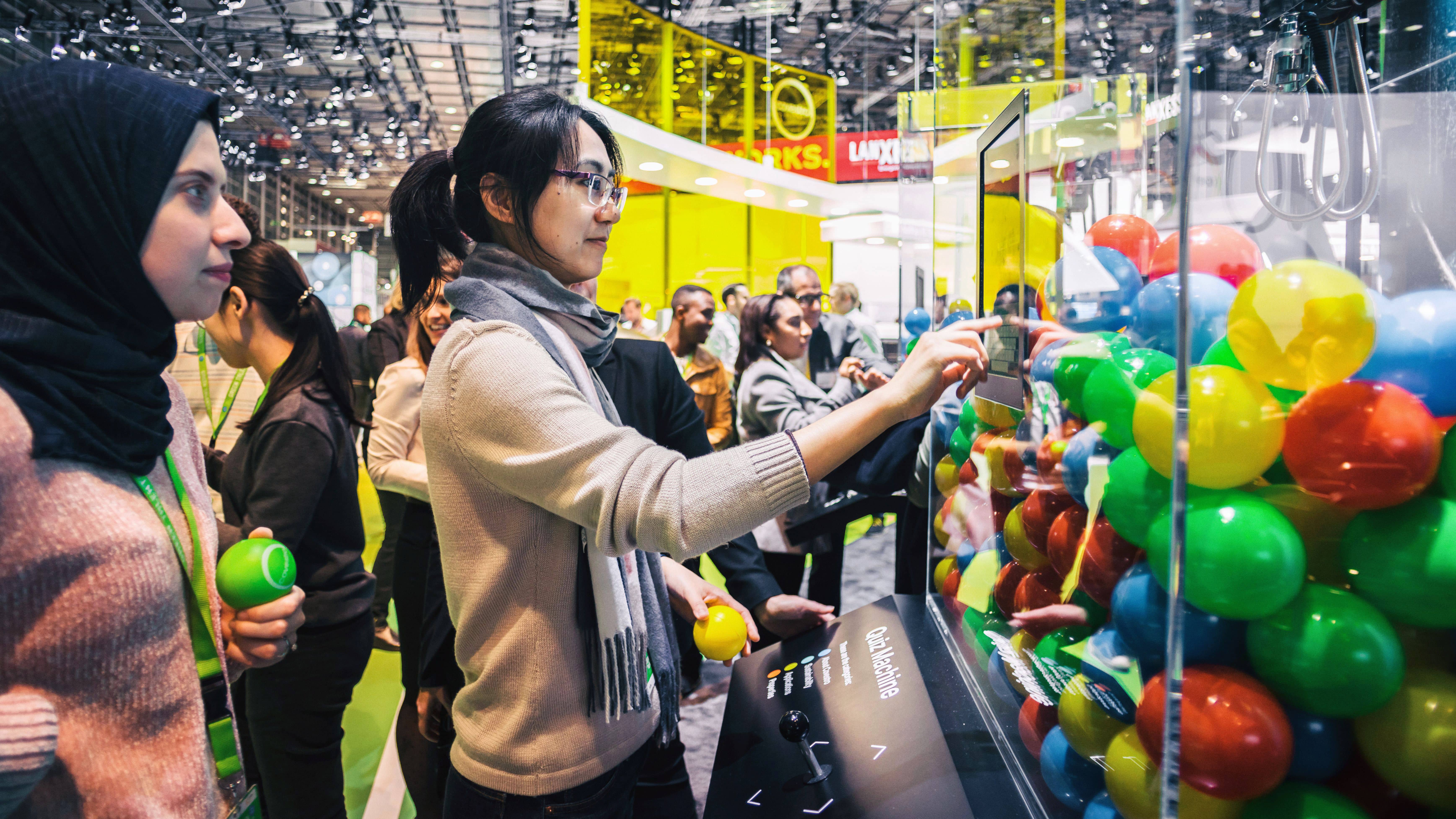 Eine Messebesucherin startet über den Bildschirm am Greifarmautomaten-Exponat das Covestro-Quiz