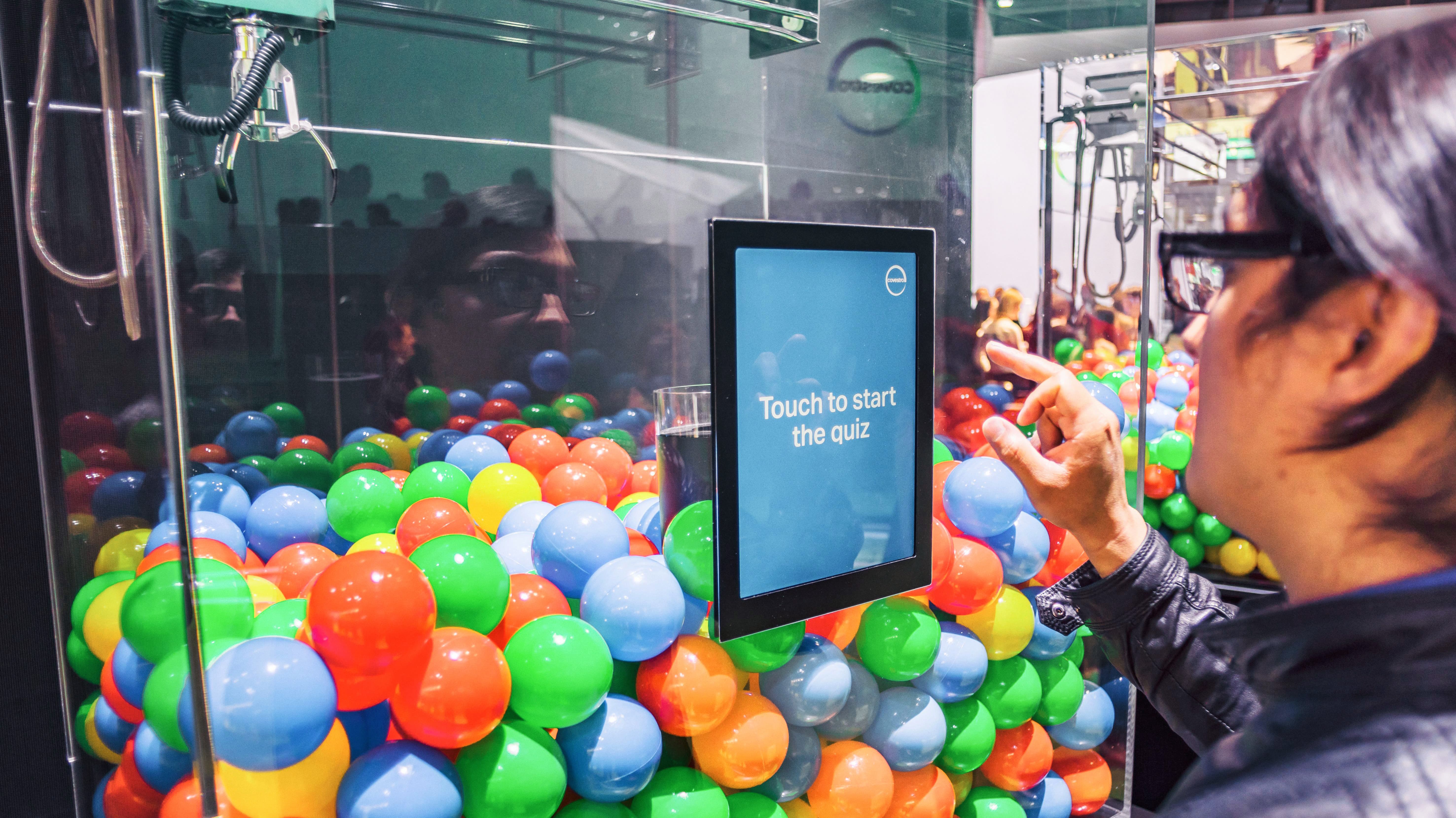 Ein Messebesucher startet über den Bildschirm am Greifarmautomaten das Covestro-Quiz