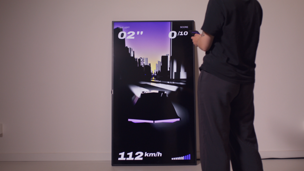 Person steht vor Bildschirm und bedient diesen mit dem Smartphone, Storefront Racer interaktive Gamification
